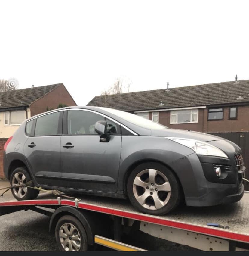 Grey Peugeot 3008 on flatbed truck for scrapping