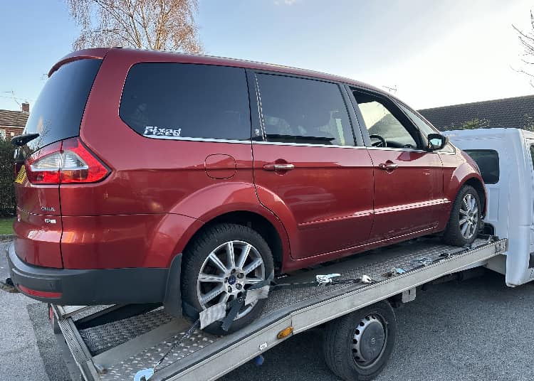 Red Ford Galaxy on recovery truck for scrapping