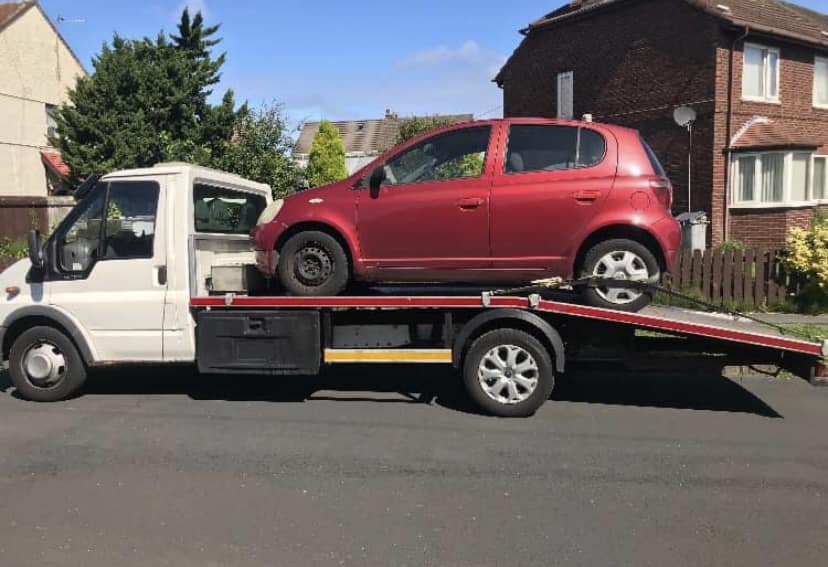 Red Toyota Yaris loaded on recovery truck in Wirral